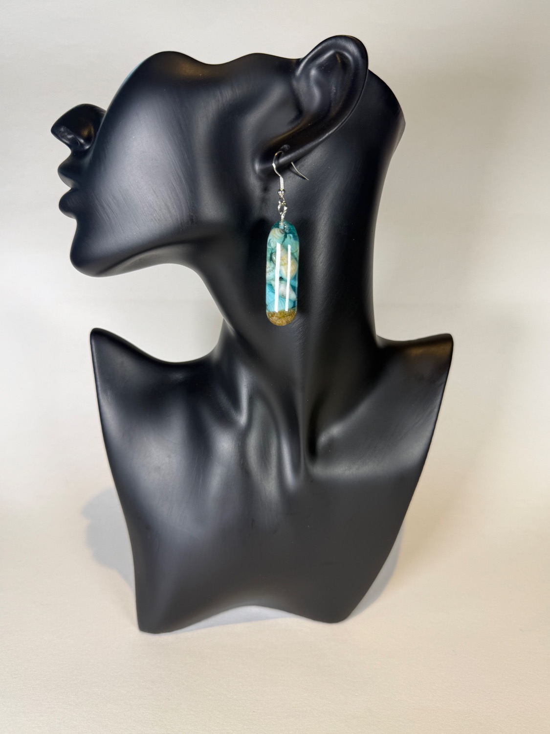 Teal capsule earrings with seashells inside