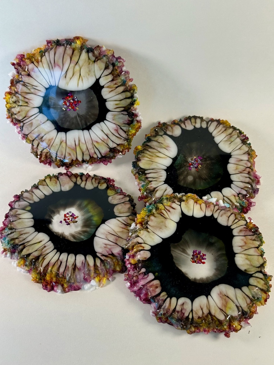 Set of 4 black resin coasters with white petal ring and multicolour gem crystal edges