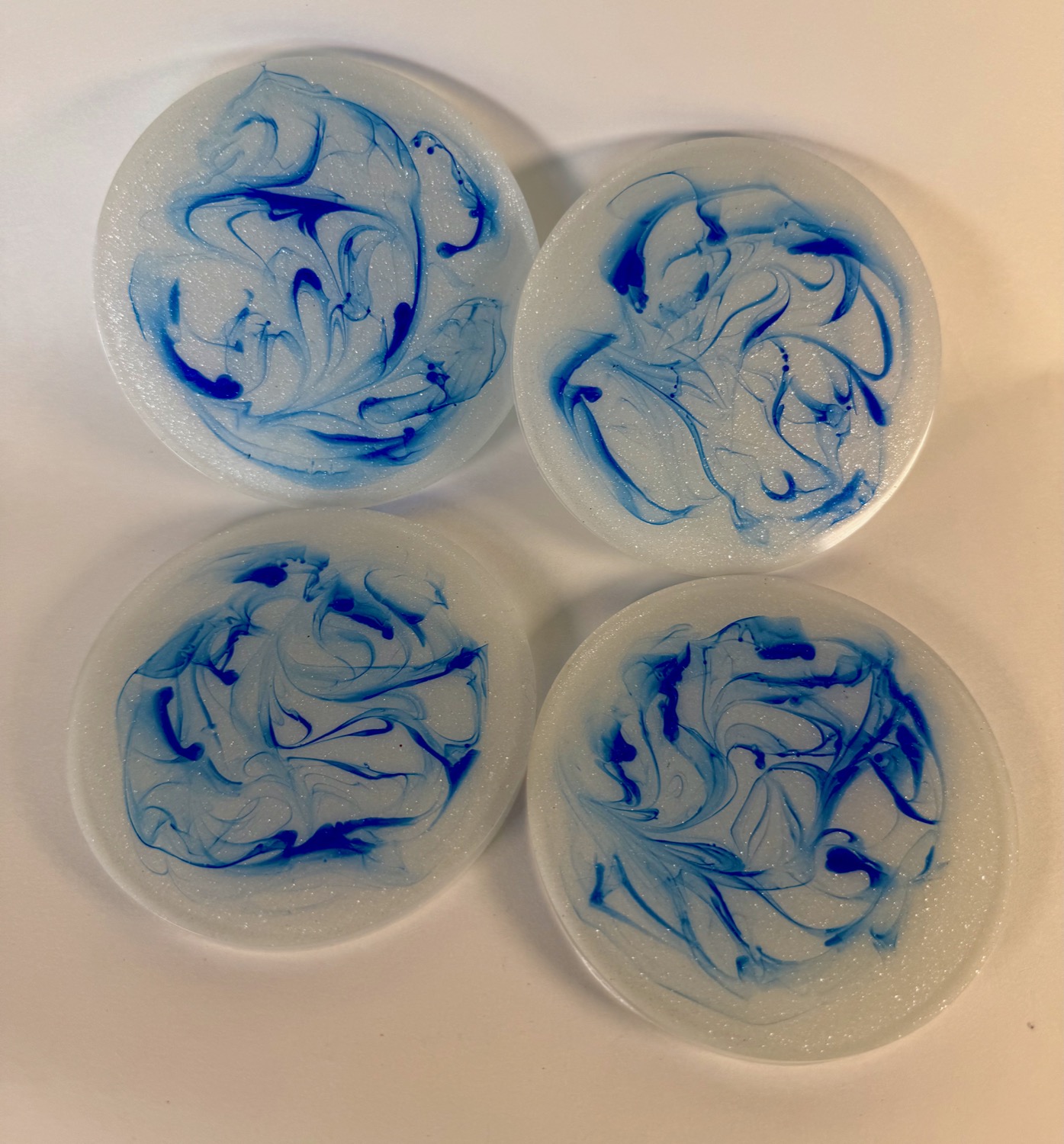 Set of 4 white resin coasters with blue marble swirl pattern