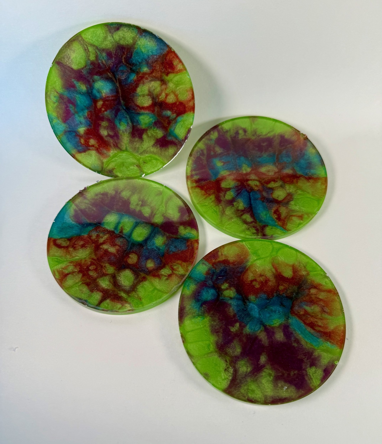 Set of 4 lime green resin coasters with rainbow red blue and maroon tie-dye pattern