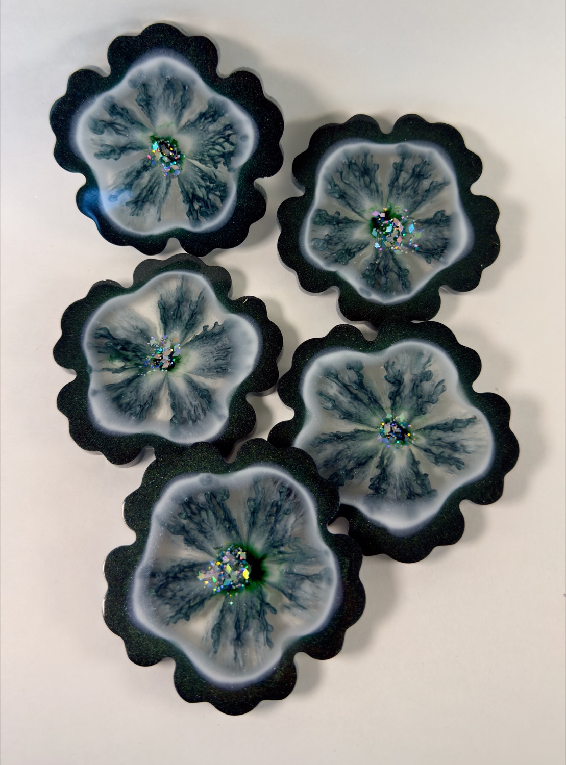 Set of 5 flower-shaped resin coasters with teal green glitter edges, white centres and holographic sparkle