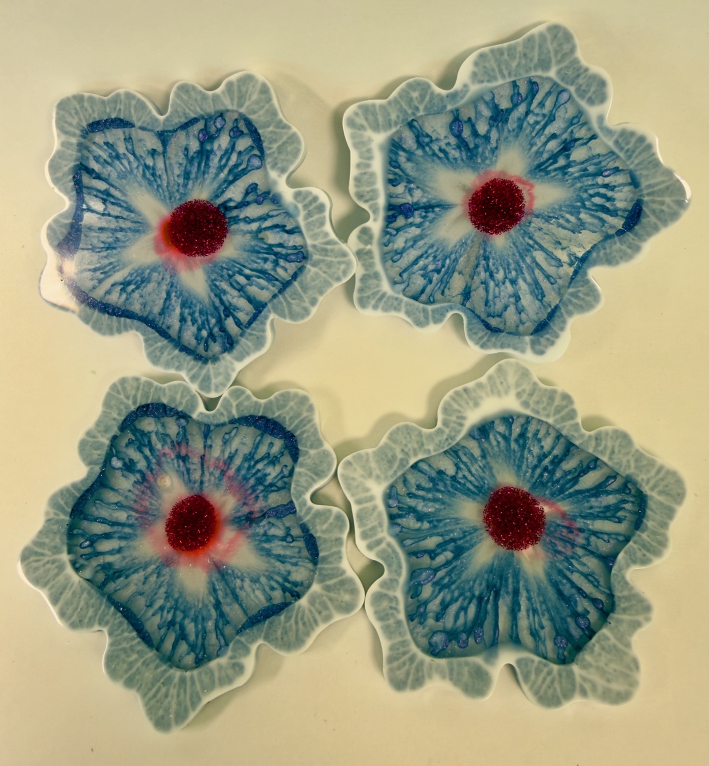 Set of 4 flower-shaped resin coasters with blue petals, pale blue ruffled edges and red glitter centres