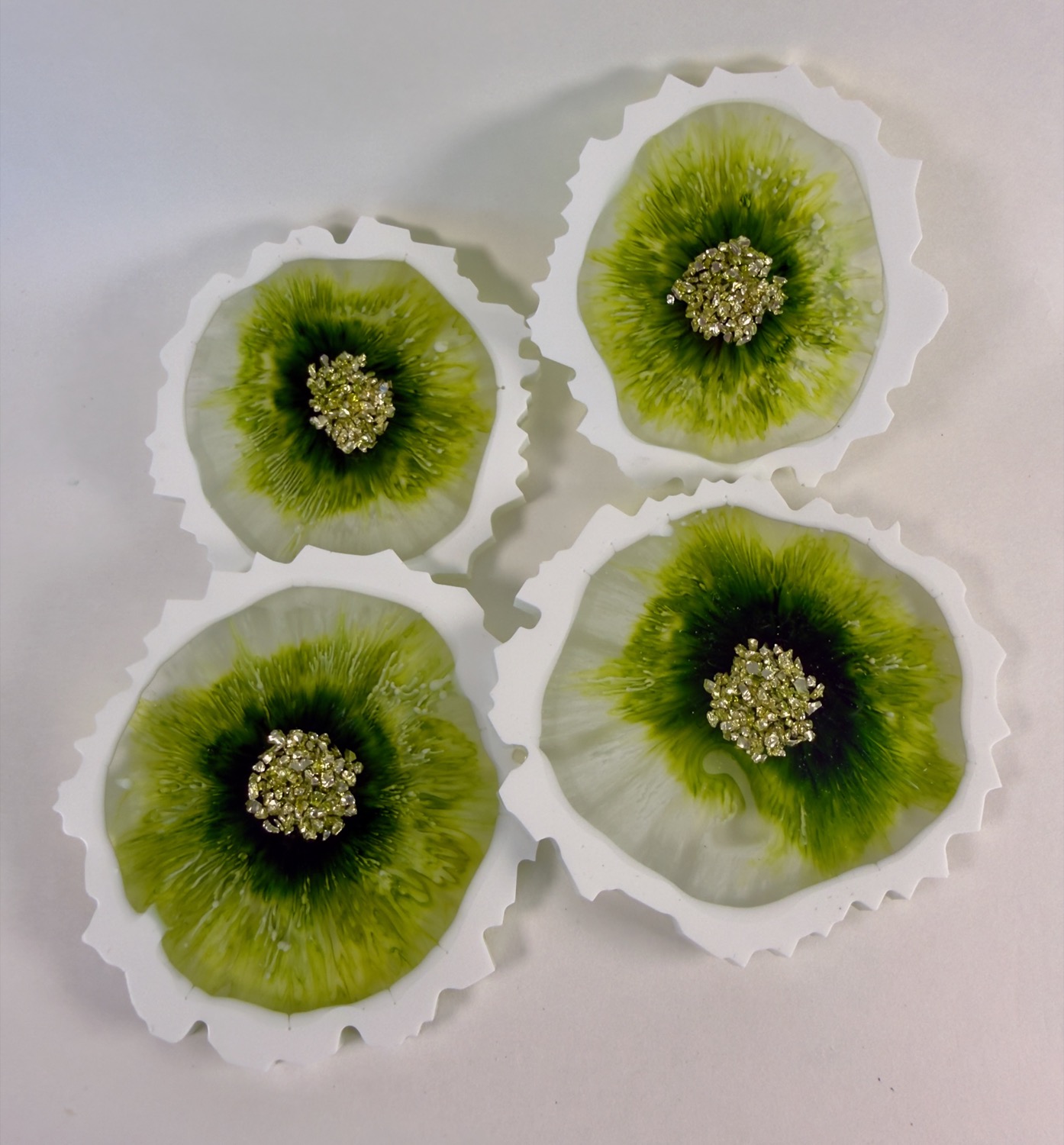 Set of 4 flower-shaped resin coasters with green petals, white ruffled edges and crystal druzy centres