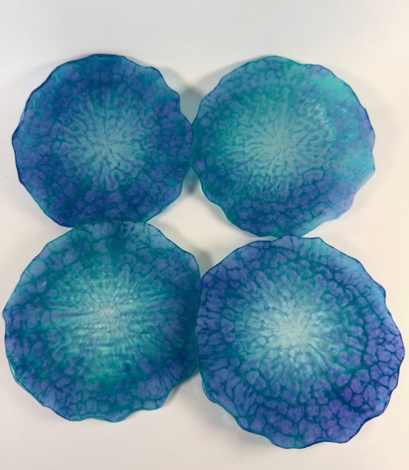 Set of 4 flower-shaped resin coasters with blue, teal and purple cell pattern and ruffled edges