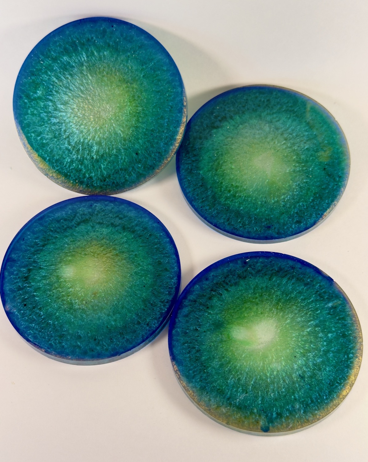 Set of 4 round teal and green geode resin coasters with shimmer sunburst centres