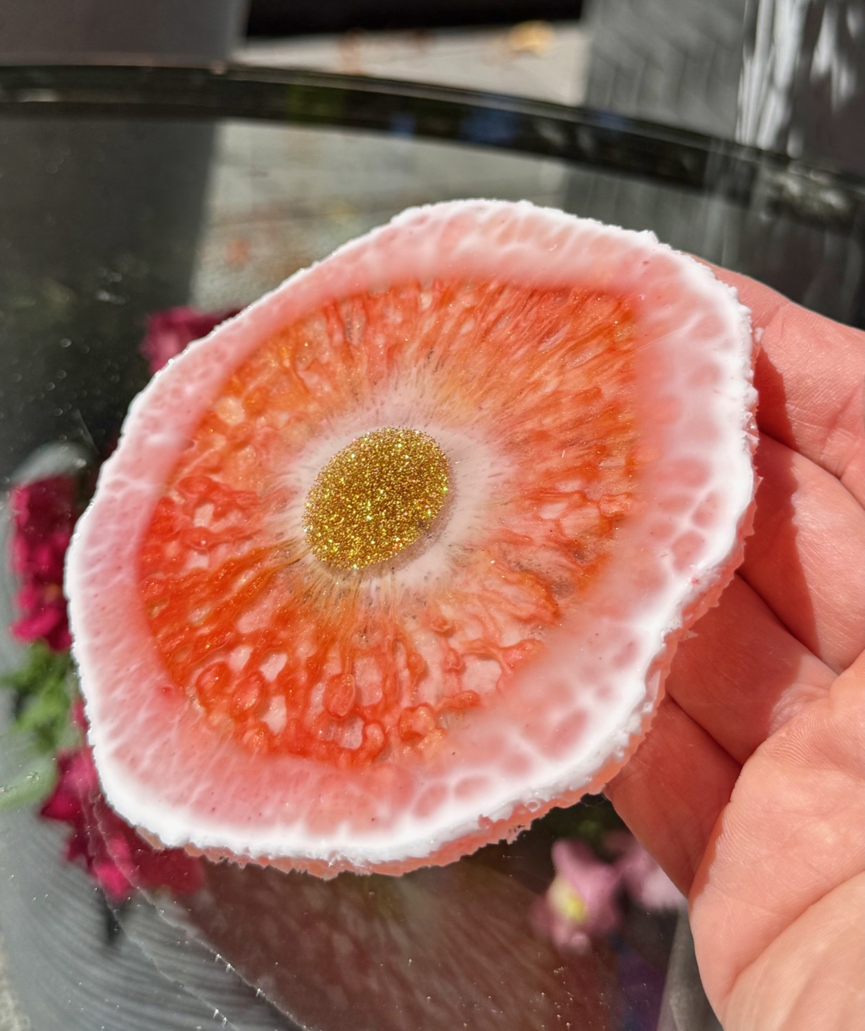 Coral Sunburst coaster held in hand outdoors