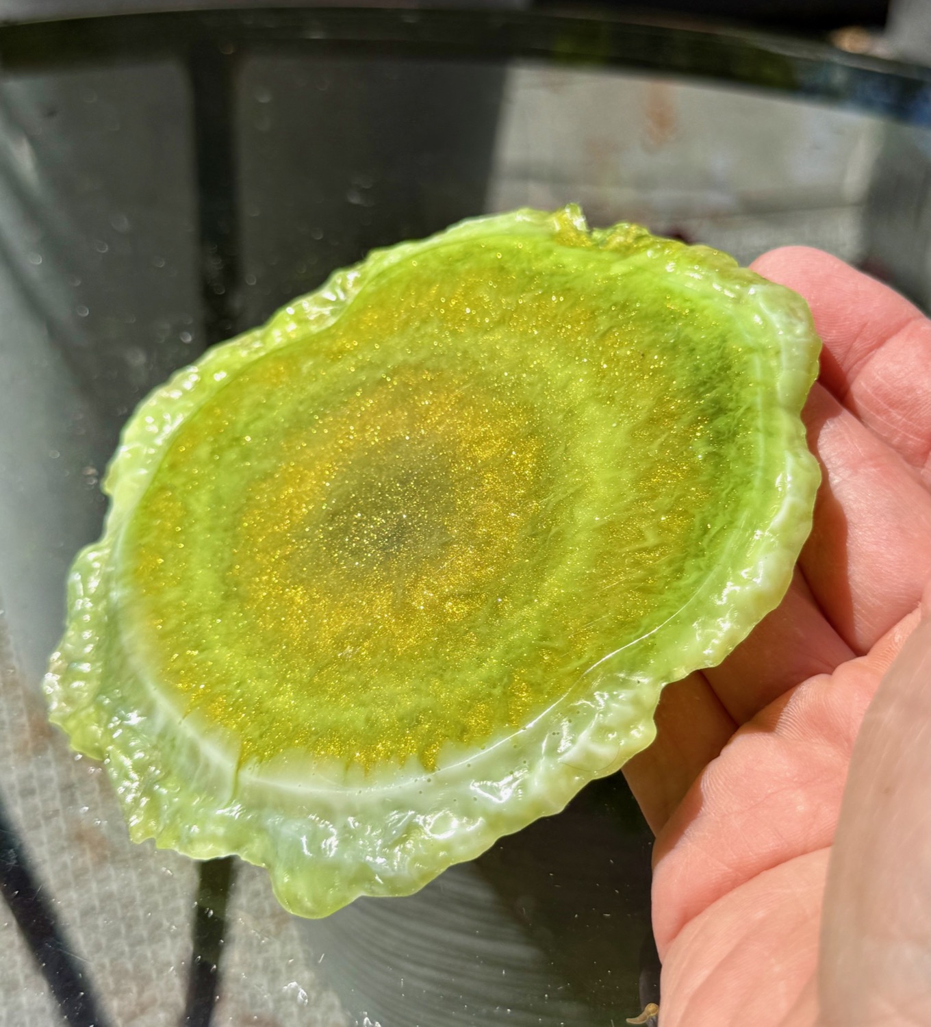 Olive Gold Geode coaster held in hand outdoors